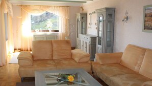 A living room with a beige sofa set, a glass coffee table with a flower, and a cabinet with decorative lights. - Uitzicht op Droomlocatie (Annaberg-Buchholz)
