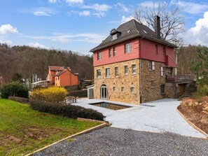 A two-story stone house with a red roof and a small balcony. - Luxury Chalet in Jalhay With Private Sauna (Jalhay)