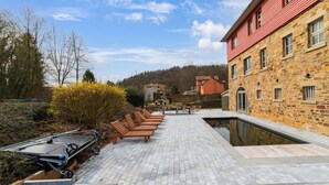 A courtyard with a pool, lounge chairs, and a stone building with a red roof. - Luxury Chalet in Jalhay With Private Sauna (Jalhay)