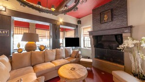 A cozy living room with a large beige sofa, a small round wooden table, and a fireplace. - Luxury Chalet in Jalhay With Private Sauna (Jalhay)