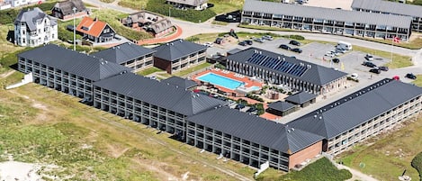 Ilmakuva hotellikompleksista, jossa on useita rakennuksia, uima-allas ja pysäköintialue.