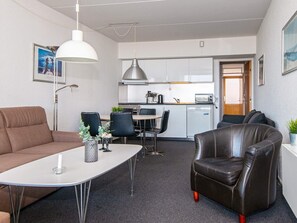 A compact living space with a kitchenette, a dining area, a sofa, a coffee table, and a leather armchair. - 4 Person Holiday Park Home in Fano (Fano)