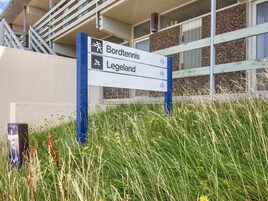 Un panneau de signalisation indiquant la direction à suivre, avec des flèches pointant vers « Bordtennis » et « Legeland ».