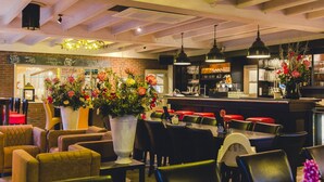 A restaurant interior with wooden beams, hanging pendant lights, and a bar area.
