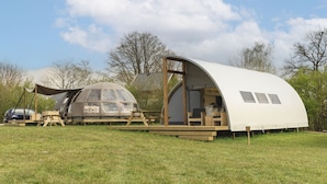 A modern, dome-shaped mobile home with a large open patio area and a covered seating area.