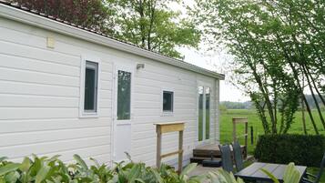 A single-story mobile home with a small porch, a table, and chairs.