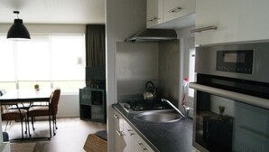 A modern kitchen with a stove, sink, and microwave. There is a dining area with a table and chairs. - Cosy Holiday Home in Appelscha With a Great View (Appelscha)