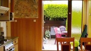 Una cocina con armarios de madera, una estufa y un comedor con sillas y una mesa.
