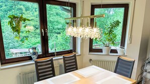A dining area with a table, chairs, and a view of greenery through large windows. - Kersten by Interhome (Essen)