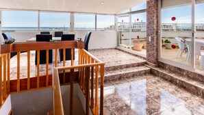 A spacious balcony with a view of the sea, a wooden railing, and a seating area with chairs and a table. - Apartment Jazmin by Interhome (Salou)