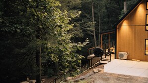 A wooden cabin with a staircase leading to a deck, surrounded by trees. - Waterview. Hot Tub. Gas Firepit. Lancaster 40 min. (Airville)