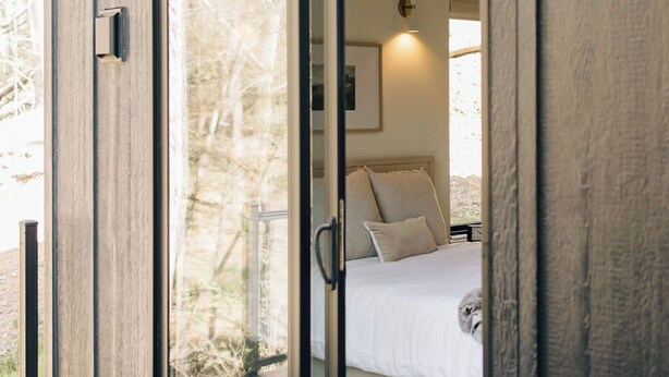 A bedroom with a sliding glass door, a bed with white bedding, and a nightstand. - Waterview. Hot Tub. Gas Firepit. Lancaster 40 min. (Airville)