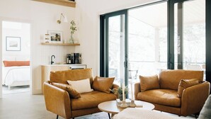 A modern living room with two leather sofas, a coffee table, and a kitchen area with a sink and countertop. - Waterview. Hot Tub. Gas Firepit. Lancaster 40 min. (Airville)