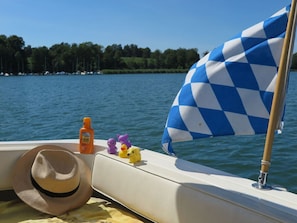 A boat with a blue and white checkered flag, a sun protection bottle, and toy ducks on the deck.