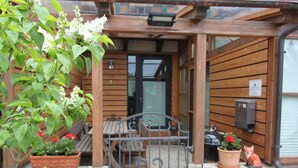 A wooden exterior with a metal gate, a bench, and potted plants.