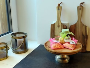 A wooden cutting board with a cake and a small plant on it, placed on a black countertop.