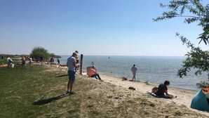 A beach with people relaxing and walking along the shore. - Sunny Apartment Directly on the Heegermeer (Heeg)