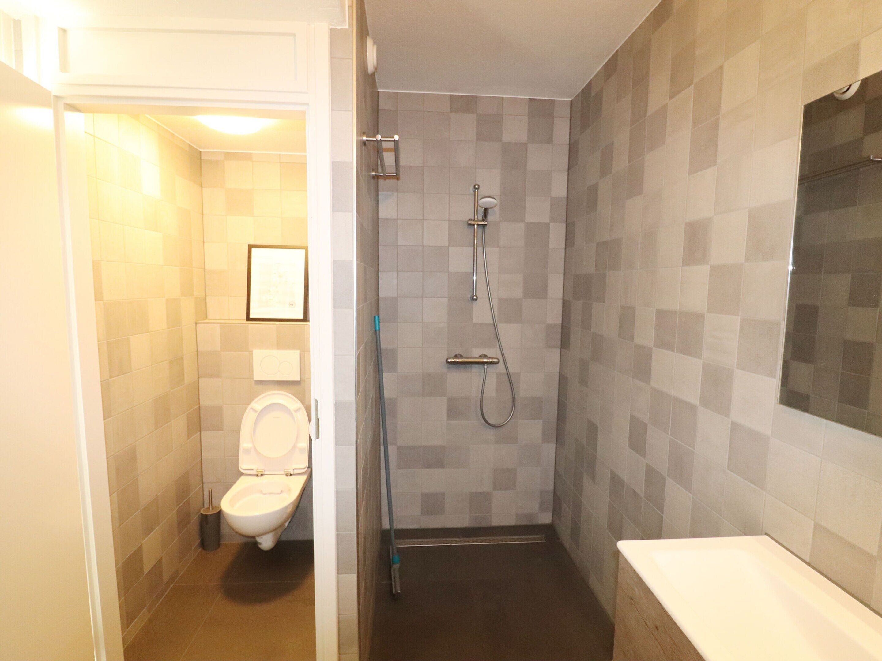 A bathroom with a toilet, a shower, and a sink.