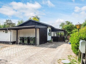 A building with a garage, a covered outdoor area, and a paved driveway.
