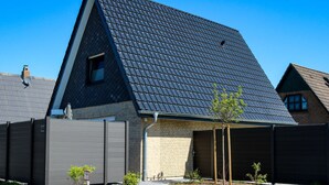A modern residential building with a sloped roof, a brick facade, and a covered garage. - Maiwaldo House Comfortable Vacation Home (Wurster Nordseeküste)