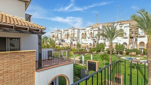 Zona residencial con edificios de varios pisos, un patio cercado y palmeras.