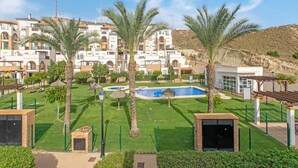 Un resort con piscina, palmeras y montañas al fondo.
