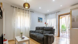 Una sala de estar con un sofá gris, una mesa de centro blanca y una lámpara colgante.