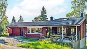 Ein eingeschossiges Holzhaus mit Veranda, Garage und Schornstein.