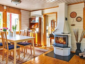 Cozy room with a central fireplace, dining area, and bookshelf.