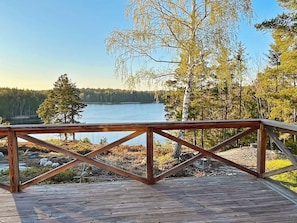 A wooden deck with a view of a lake and trees.