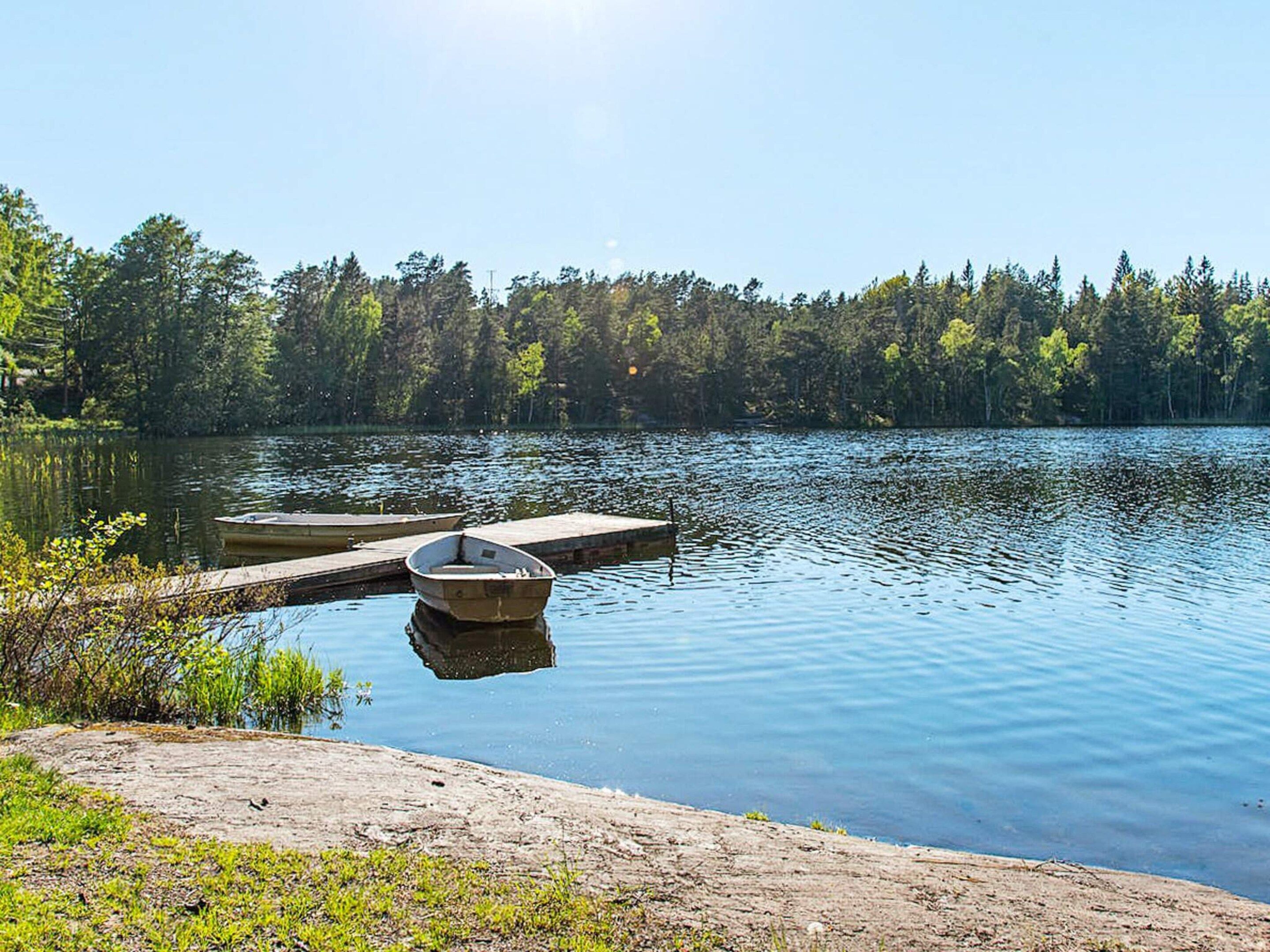 A calm lake with a wooden dock and a boat.