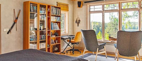 A room with a bed, a desk, two chairs, and a large bookshelf.