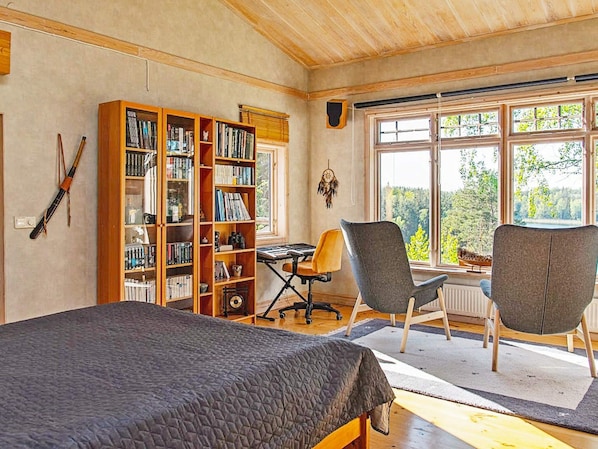 A room with a bed, a desk, two chairs, and a large bookshelf.