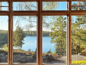 A view through a window with multiple panes, overlooking a lake surrounded by trees.