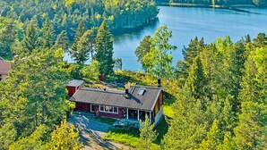 Eine Hütte mit geneigtem Dach, umgeben von dichtem Wald und einem See.