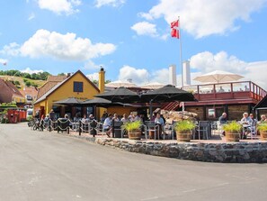 Un restaurante con terraza, paredes de piedra y una bandera.