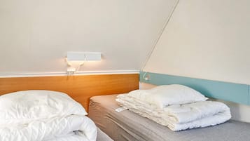 Habitación de hotel con dos camas individuales, cabecero de madera, luz de pared y un diseño sencillo y limpio.