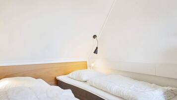 Una habitación sencilla y luminosa con dos camas y una lámpara de noche.