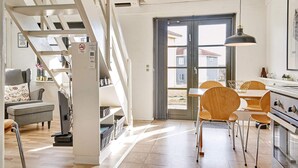A modern kitchen with a dining area, wooden chairs, and a staircase. - 5 Person Holiday Park Home in Gudhjem (Gudhjem)