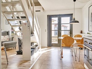 A modern kitchen with a dining area, wooden chairs, and a staircase. - 5 Person Holiday Park Home in Gudhjem (Gudhjem)