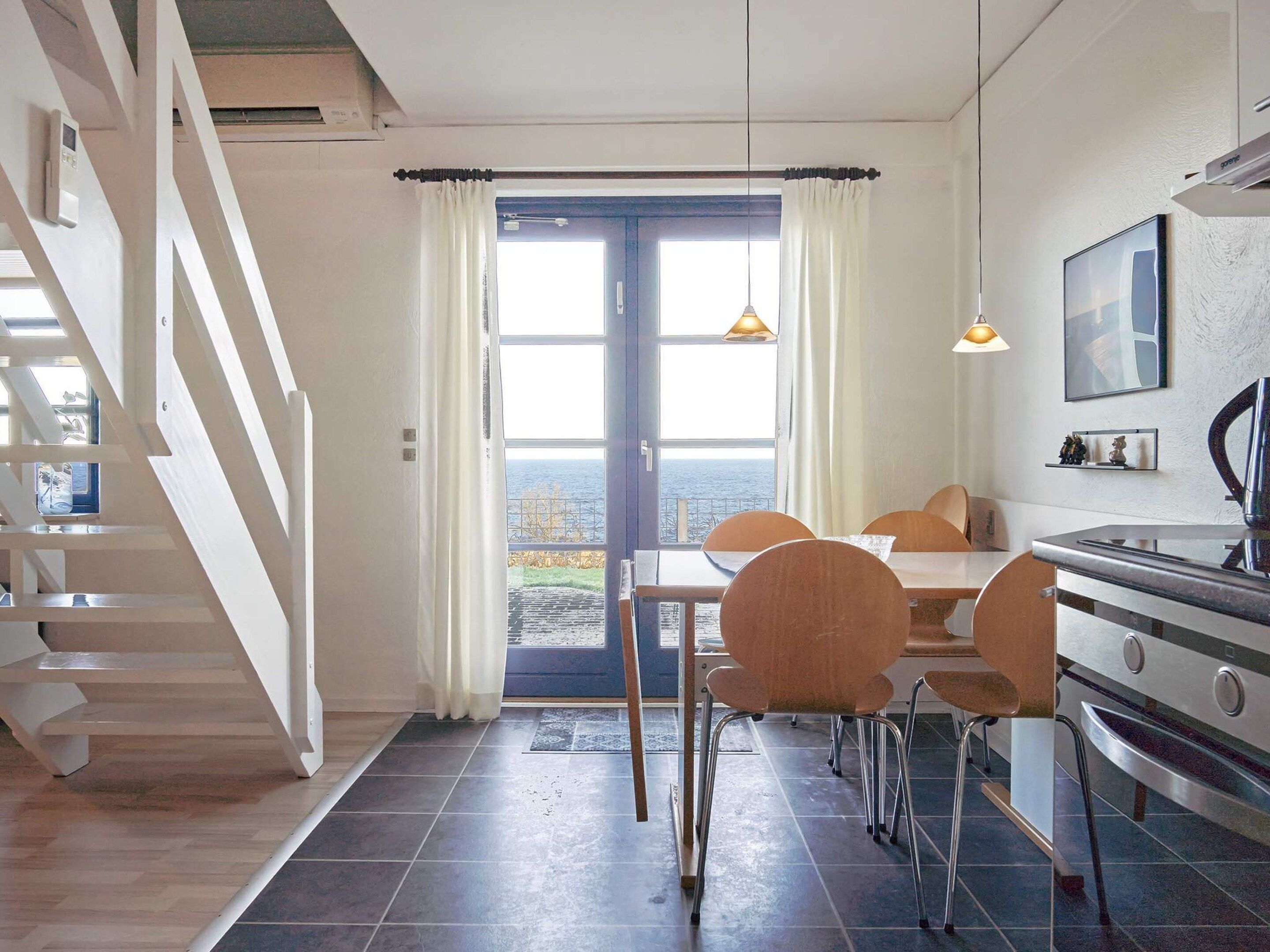 Una cocina moderna con comedor, escalera y vista al mar.