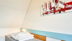 A bedroom with a bed, a bedside table, a wall-mounted artwork, and a light fixture. - 5 Person Holiday Park Home in Gudhjem (Gudhjem)