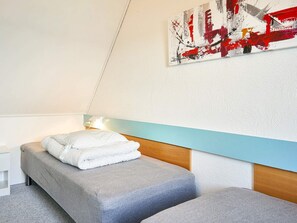 Une chambre à coucher comprenant un lit, une table de chevet, une œuvre d’art accrochée au mur et un luminaire.