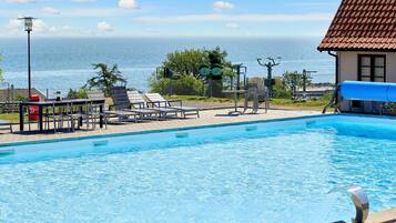 Ein Swimmingpool mit Liegestühlen und Blick aufs Meer.