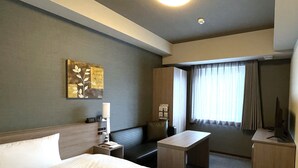 Een hotelkamer met een bed, een bureau, een stoel, een kleine tafel en een televisie.