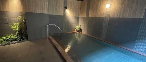 A swimming pool with tiled walls and a metal handrail.