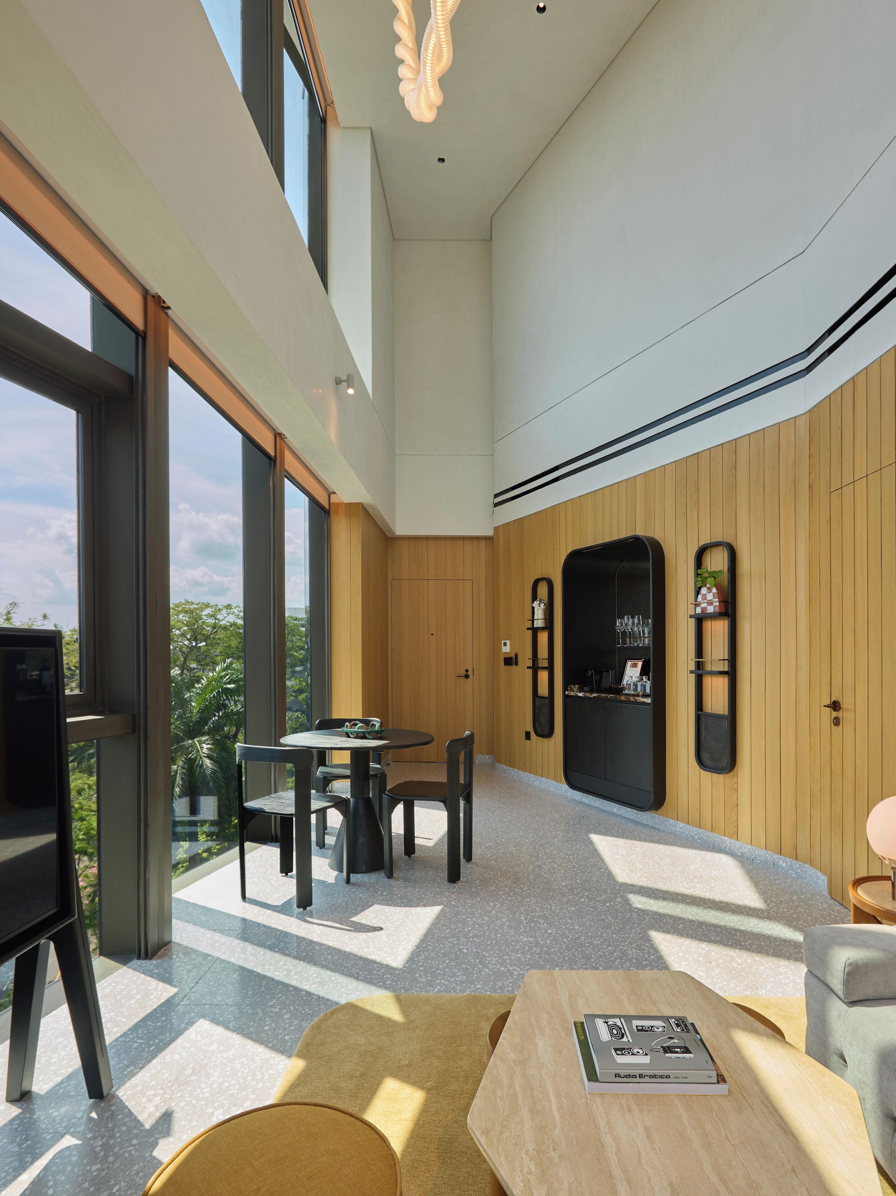 Un intérieur moderne comprenant un espace repas, un bar et de grandes fenêtres donnant sur un paysage verdoyant.