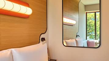 A hotel room with a wooden ceiling, a large mirror, and a bed with white linens.