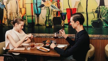 Dos personas cenando en un restaurante con un mural colorido de fondo.
