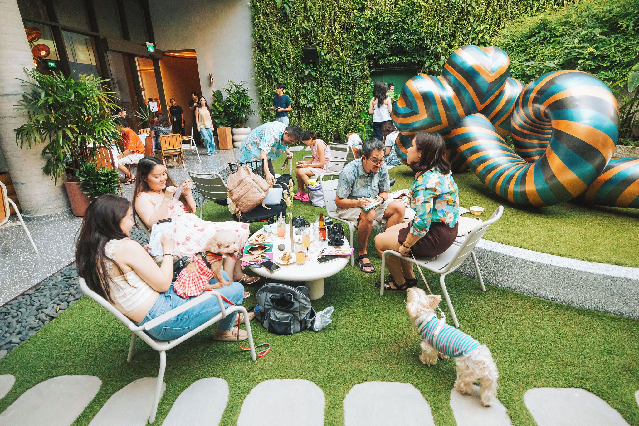 Un espace extérieur aménagé avec des tables et des chaises, entouré de verdure et d’éléments décoratifs.